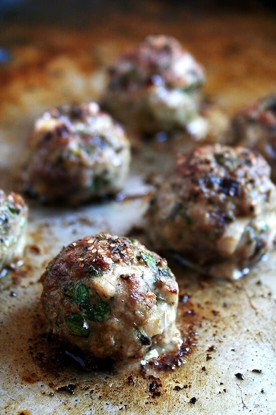 Lamb meatballs, loaded with mint and parsley, broiled, sprinkled with vinegar, and served with roasted cabbage, are perfect for Easter. // www.simonrockett.com A sheet pan of broiled lamb meatballs.