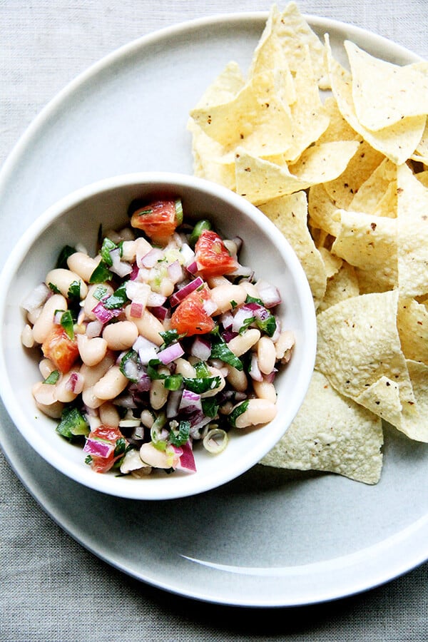 We've been eating this white bean and orange salsa, mixed with onions, lime, jalapeños, cilantro, and orange, with chips, but it would be nice tucked inside a taco or a burrito or aside spicy wings and nachos and anything else you might find yourself surrounded by on game day. // www.simonrockett.com 一碗白豆莎莎撇开薯片。