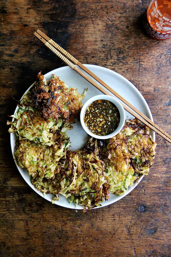 Okonomiyaki, Japanese cabbage pancakes, can be made in countless ways: okonomiyaki essentially means prepared as you like. This my favorite version I've made yet, but know that you can add to it as you like with shrimp or chicken, sesame seeds or bonito flakes, other vegetables, etc. I prefer a soy-based dipping sauce to the more traditional mayonnaise-based, and, like the corn fritters, find these as irresistible freshly fried as cold straight from the fridge. // www.simonrockett.com 一盘御好烧与酱油蘸酱。