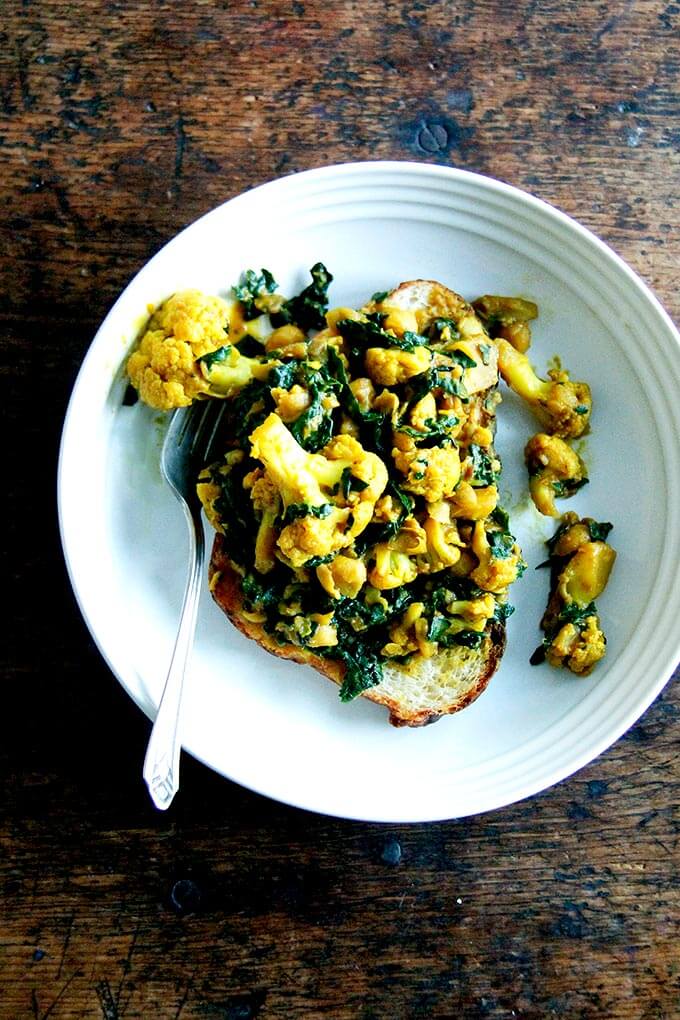 a bowl filled with bread, cauliflower, and kale scramble.
