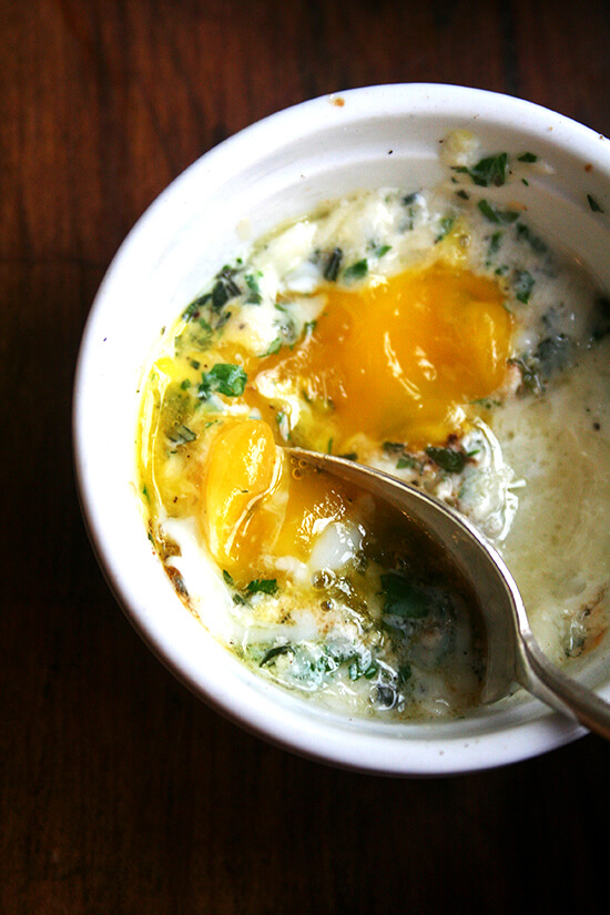 This recipe for baked eggs appeared in the New York Times Magazine in 1985, and my mother has been making them for us ever since. Topped with herbs — parsley, sage, rosemary and thyme — melted gruyère and a few splashes of Tabasco, these perfectly soft-cooked eggs are such a treat. // www.simonrockett.com 一个小模子烤用汤匙(带褶皱的荷花边蛋)。