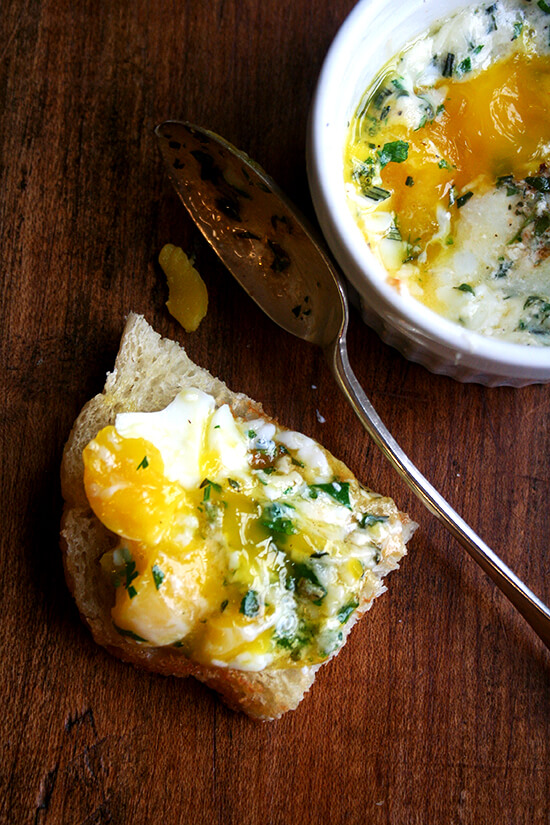 This recipe for baked eggs appeared in the New York Times Magazine in 1985, and my mother has been making them for us ever since. Topped with herbs — parsley, sage, rosemary and thyme — melted gruyère and a few splashes of Tabasco, these perfectly soft-cooked eggs are such a treat. // www.simonrockett.com 一块面包加上烤鸡蛋(带褶皱的荷花边)。