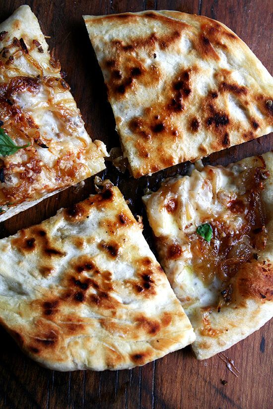 在马车的焦糖洋葱和burrata披萨撒上罗勒。