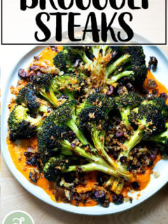 一盘烤花椰菜牛排顶部有橄榄面包屑。